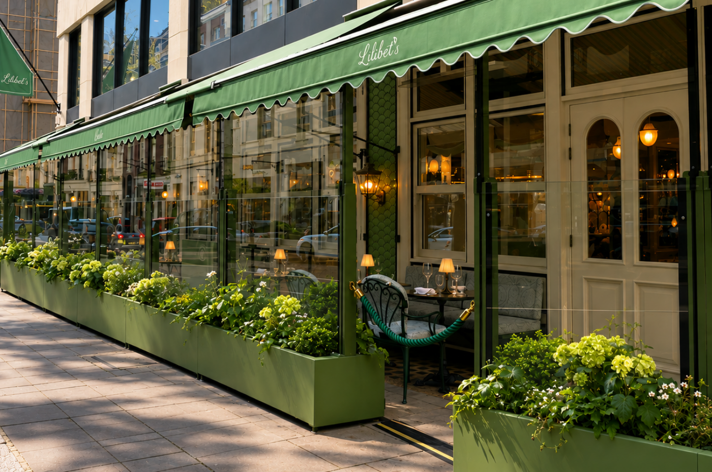 Lilibet’s Garden Terrace on Bruton Street, Mayfair — outdoor dining surrounded by seasonal planting beneath a green canopied awning.